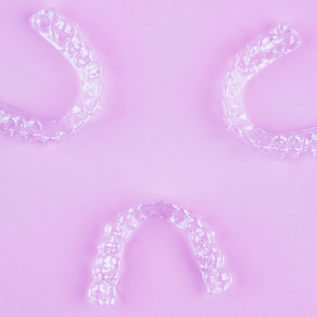 Invisible aligner teeth retainers on a pink background