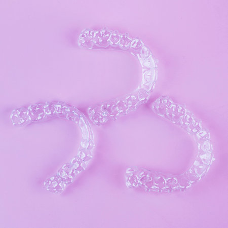 Invisible aligner teeth retainers on a pink background