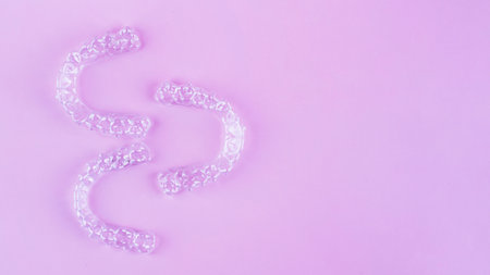 Invisible aligner teeth retainers on a pink background
