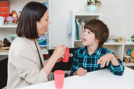 Woman speech therapist helps a child correct the violation of his speech in her office