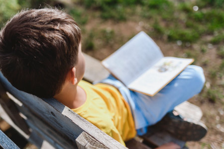 A child reads a book sitting on a bench in natureの写真素材