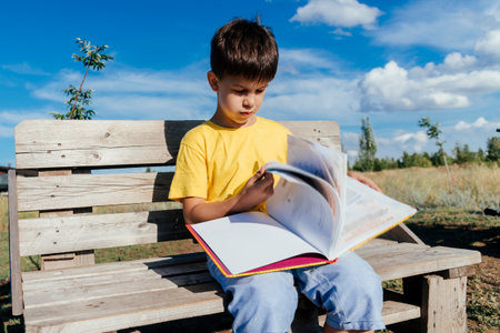 A child reads a book sitting on a bench in natureの写真素材