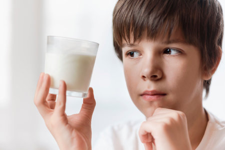 Beautiful child holding a glass of milk in his handの写真素材