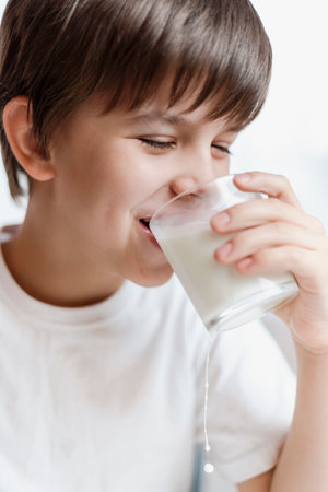 Cute child drinking milk at home and smiling on white backgroundの写真素材