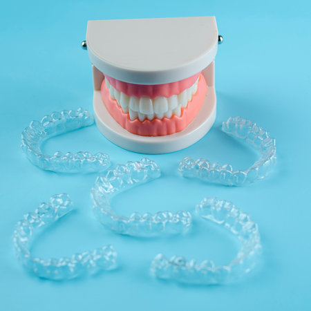 Close-up. Transparent aligners for artificial jaw teeth on a blue background
