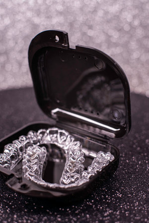 Transparent aligners spin in a black container. Plastic removable teeth correction retainers.