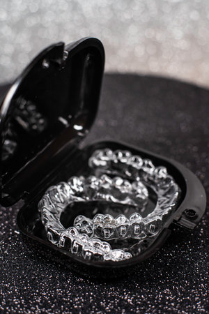 Transparent aligners spin in a black container. Plastic removable teeth correction retainers.の写真素材