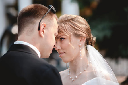 A happy bride and groom, holding hands, stroll through the city on their wedding day. The newlyweds, in love, take photos together.の写真素材