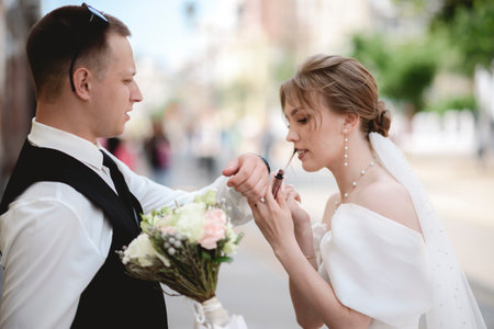 Happy newlyweds embrace. A happy bride and stylish groom hold hands and stroll through the city.の写真素材