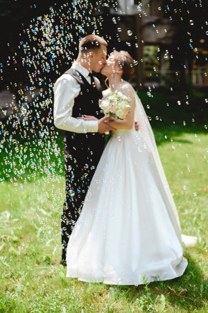 A beautiful wedding photo. Happy newlyweds take photos in a park with soap bubbles on a sunny day.の写真素材
