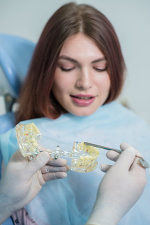 the orthodontist shows the carious cavity in the patient's chewing toothの写真素材