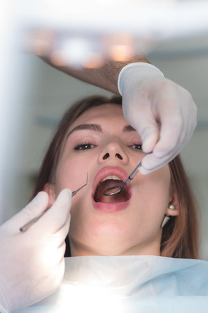 the doctor examines the oral cavity of the patientの写真素材