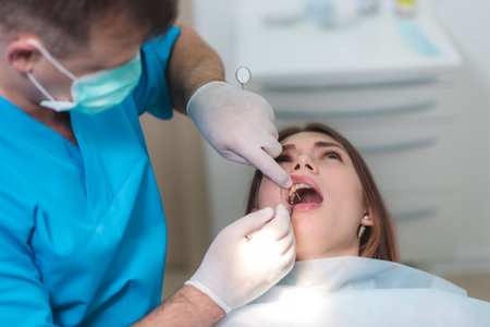 the doctor examines the oral cavity of the patientの写真素材