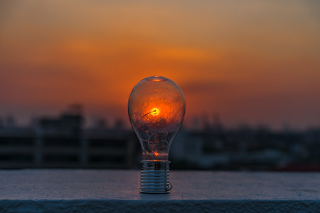 Bright idea concept, electric light bulb glowing from the sunset.の写真素材