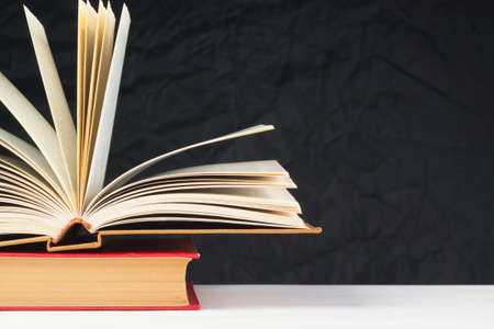 Old books on the table, on a black background, white tableの写真素材