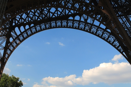 View of sky and clouds from beneath the arch of the Eiffel Tower on a sunny spring day  in Paris,...