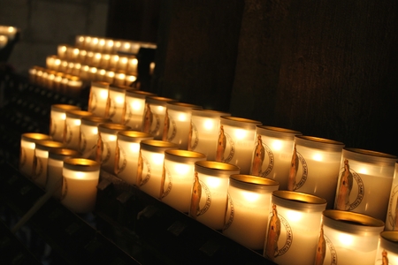 A row of glowing votive candles, each representing an individual prayer, in Notre Dame Cathedral in Paris, Franceのeditorial素材