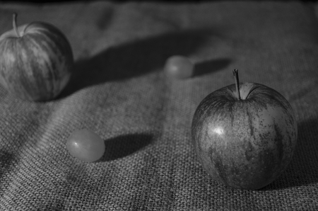 Rustic still life of apples and grapes on hessian in black and whiteの写真素材