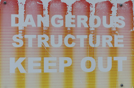 Faded sign warning of a dangerous structureの写真素材