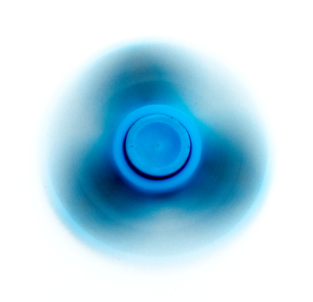 Blue fidget spinner rotating on a white backgroundの写真素材
