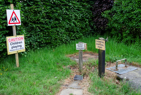 Chemical toilet and grey waste disposal point on a camp site with a warning sign for children...