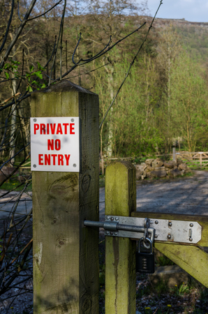 A sign attatched to a wooden gate post and locked gate. The sign states that the area is private and no entry is allowedの写真素材