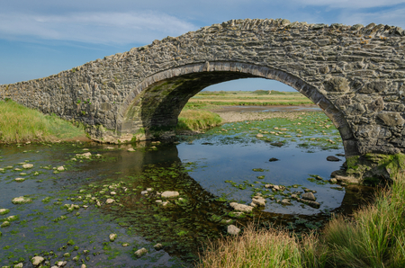 The old arched bridge which crosses the River next to the village of Aberffraw on the Welsh Island...