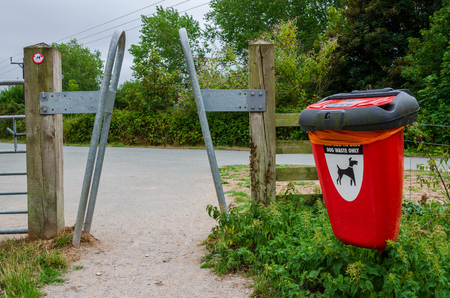 A squeeze barrier at the entrance to a footpath through a country park with a dog mess bin at the side of the gateway.の写真素材