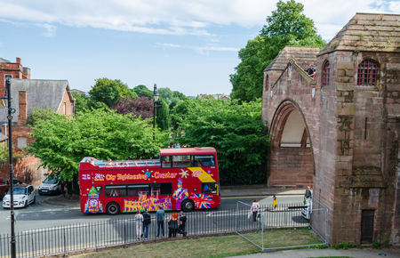 Chester, UK: Aug 6, 2018: A sightseeing double deck bus drives under Newgate in the historic city of Chester.のeditorial素材