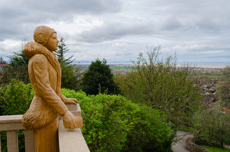 Prestatyn, UK; April 2018; Chainsaw sculpture of a woman dressed in 1930's style looks out across Prestatyn towards the sea from the Hillside Gardens Shelter.のeditorial素材