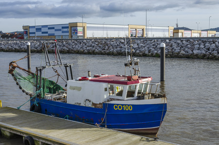 RHYL, UK - JAN 29, 2019: A fishing boat is moored at Rhyl Harbour, with the Cei Marina retail park...