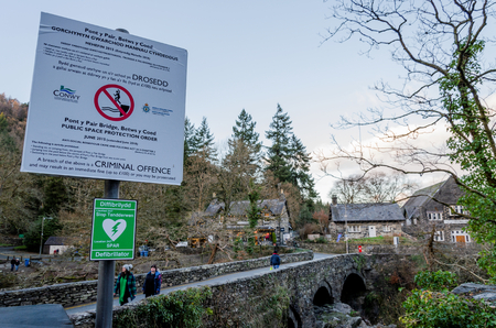 Betws y Coed, UK - Feb 2, 2019: The Pont-y-Pair bridge in Betws-y-Coed crosses the Afon Llugwy River. Signs warn of danger and fines for people who jump from the bridge into the river below.のeditorial素材
