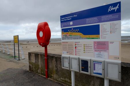 Rhyl, UK: Jan 7, 2020: A lifebouy holder and beach information sign on the promenade.のeditorial素材