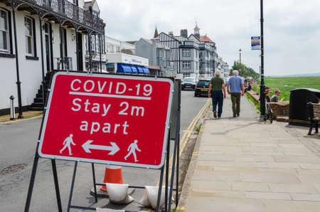 Parkgate, UK: Jun 17, 2020: A general street scene with red signs advising about social distancing...