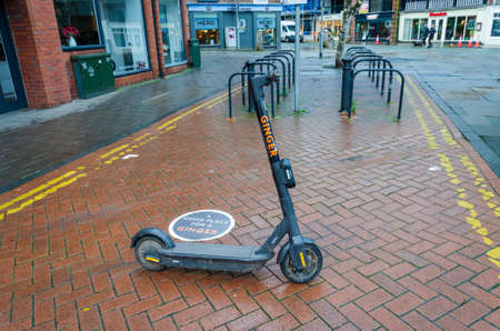 Chester; UK: Jan 29, 2021: An electric scooter operated by Ginger waits to be hired on a damp Friday...