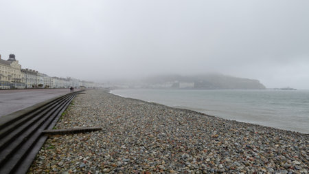 Llandudno, UK: Mar 18, 2021: The promenade which is usually popular with tourists all year is very quiet during the covid pandemic lockdown. Seen here on a grey, misty day.のeditorial素材