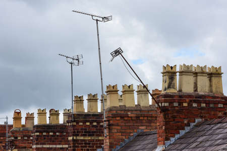 Clay chimney pots on the top of red brick chimney stack of a residential houseの写真素材