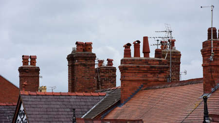 Clay chimney pots on the top of red brick chimney stack of a residential houseの写真素材