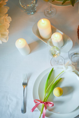 Serving a festive table for Easter, flowers, champagne glasses, eggs and cakes, candles serving,...