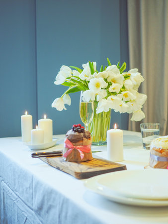 Serving a festive table for Easter, flowers, champagne glasses, eggs and cakes, candles