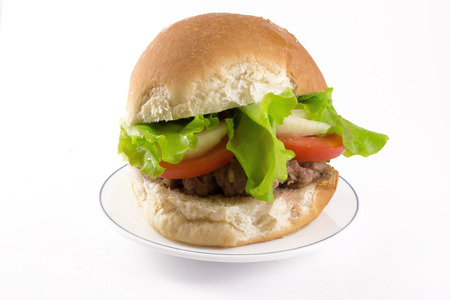 A single homemade burger with lettuce and tomato isolated on whiteの写真素材
