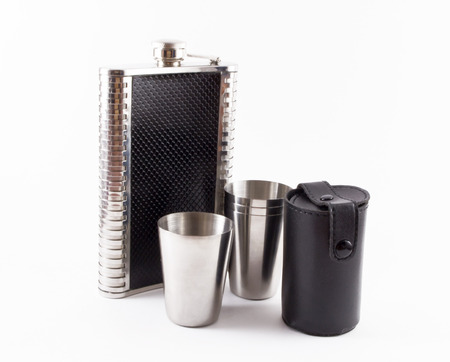 A leather hip flask and four metal travel shot glasses and a black leather caseの写真素材