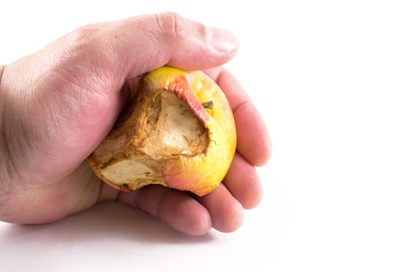 A human male hand clenching an aging apple with mouldの写真素材
