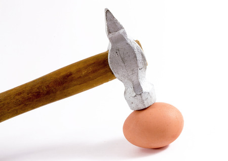 Close up of a silver hammer head hitting an unbroken egg in close upの写真素材