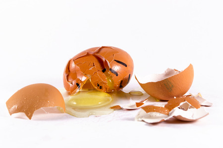 An egg witha  face lies broken and crushed with yolk spilling outの写真素材