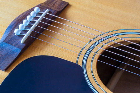 Guitar strings and the bridge with the sound hole and visible rosette