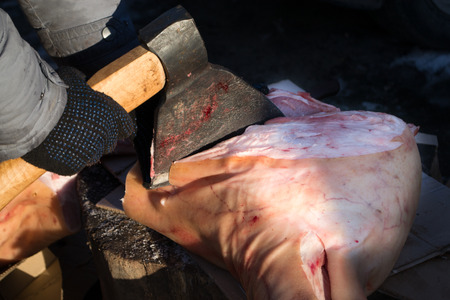 A butcher uses an axe to cut raw pork ready to sellの写真素材