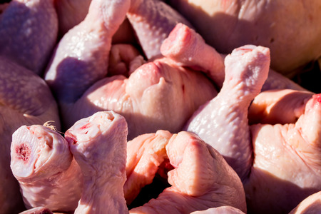 Uncooked raw chicken pieces await purchase in a stack at a local marketの写真素材