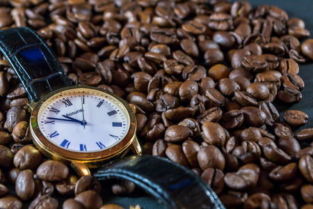 Fresh organic coffee beans and a leather and gold watch time for coffeeの写真素材