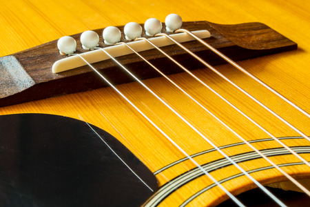 Freshly strung guitar strings against a saddle and bridge of an acoustic guitarの写真素材